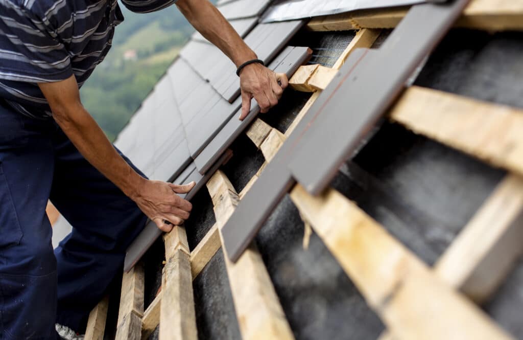 A close up of a roofer installing slate tiles.