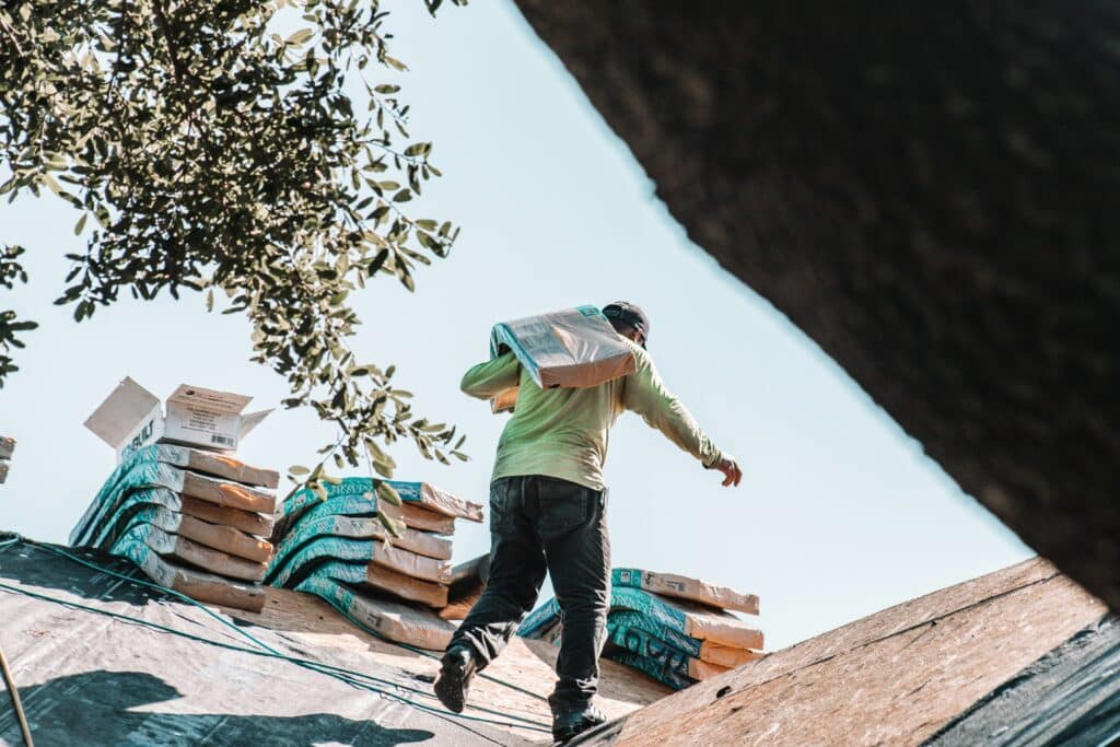 Roofer carrying materials across a residential roof during replacement.